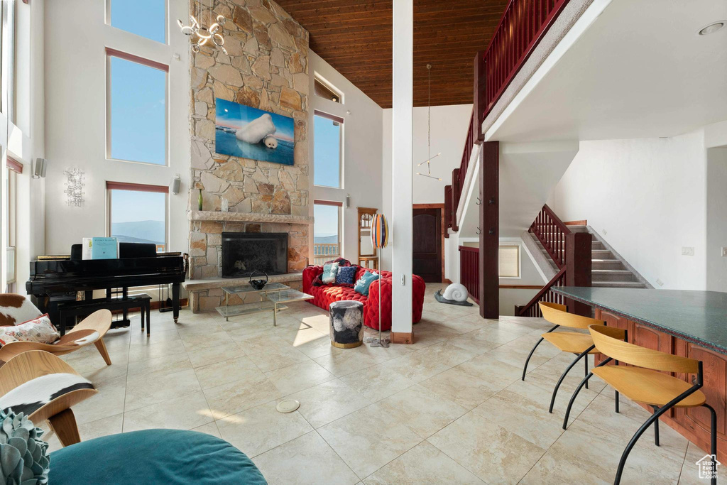 Living room featuring wood ceiling, a towering ceiling, and a stone fireplace