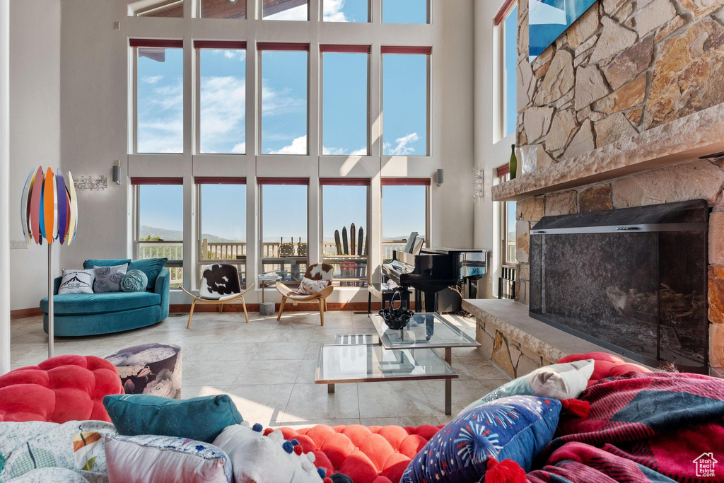 Tiled living room featuring plenty of natural light, a towering ceiling, and a fireplace