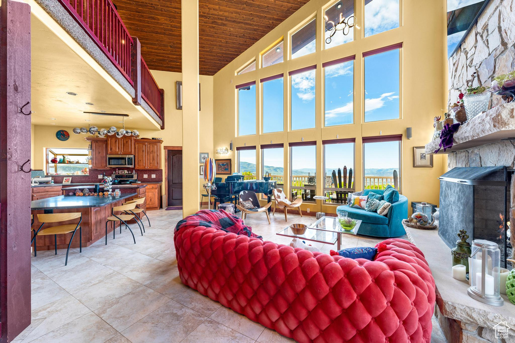 Tiled living room with a stone fireplace, wooden ceiling, and high vaulted ceiling