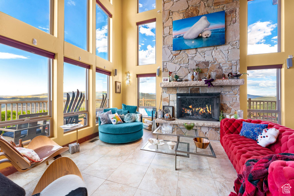 Tiled living room featuring a high ceiling, a healthy amount of sunlight, and a fireplace