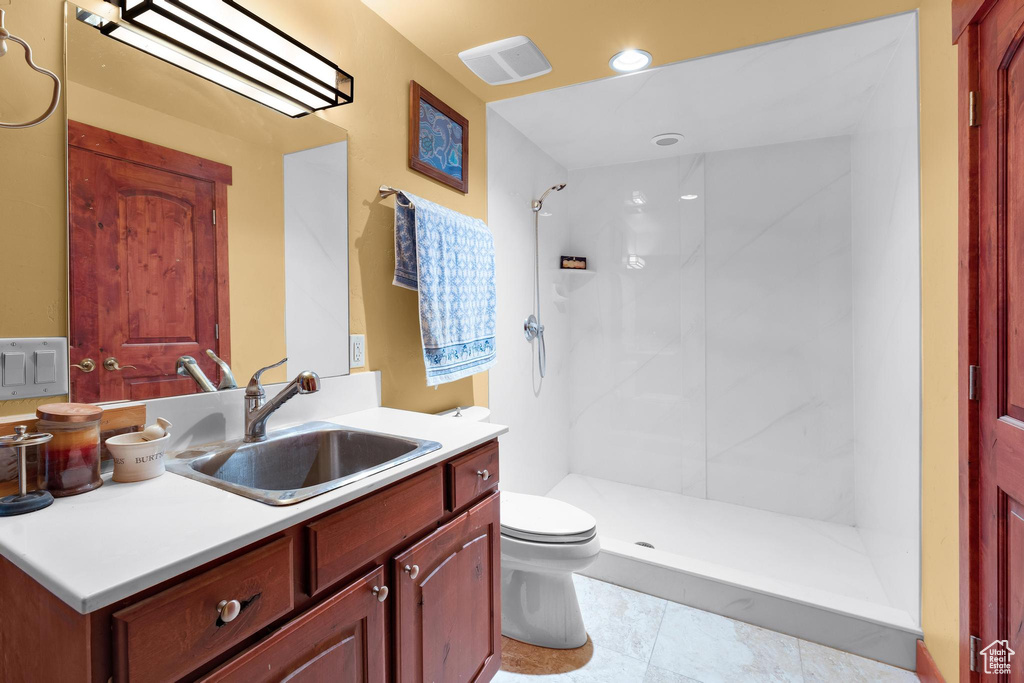 Bathroom with tile flooring, a shower, vanity, and toilet