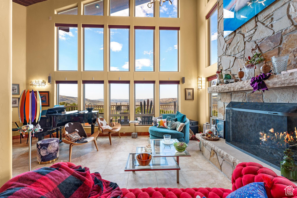 Tiled living room featuring a high ceiling, a fireplace, and plenty of natural light