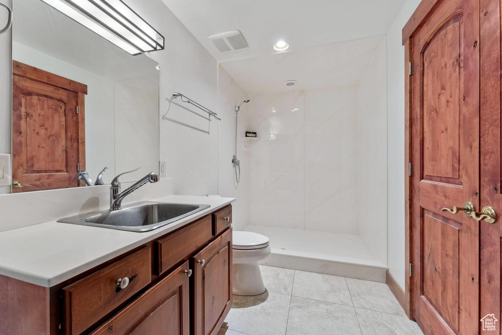 Bathroom with vanity, toilet, a tile shower, and tile patterned floors