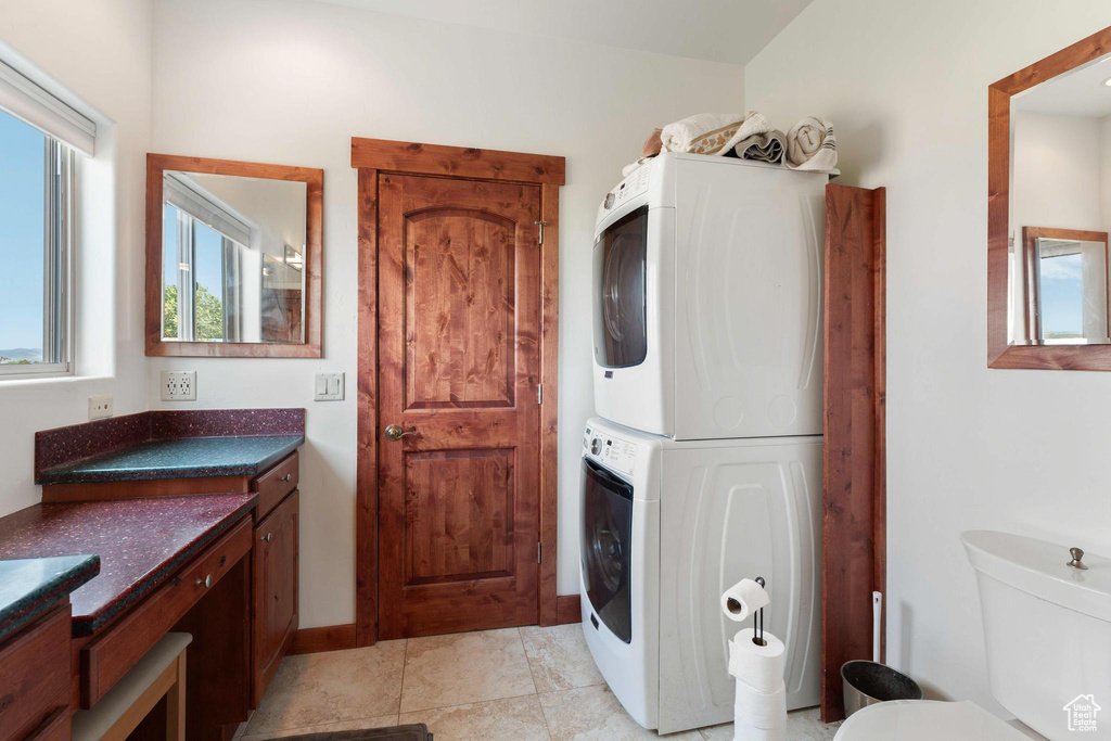 Clothes washing area with stacked washer / dryer and light tile patterned flooring