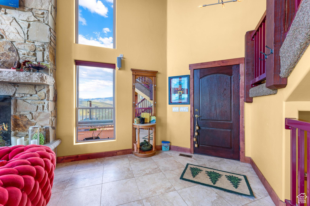 Tiled entrance foyer with a towering ceiling and a fireplace