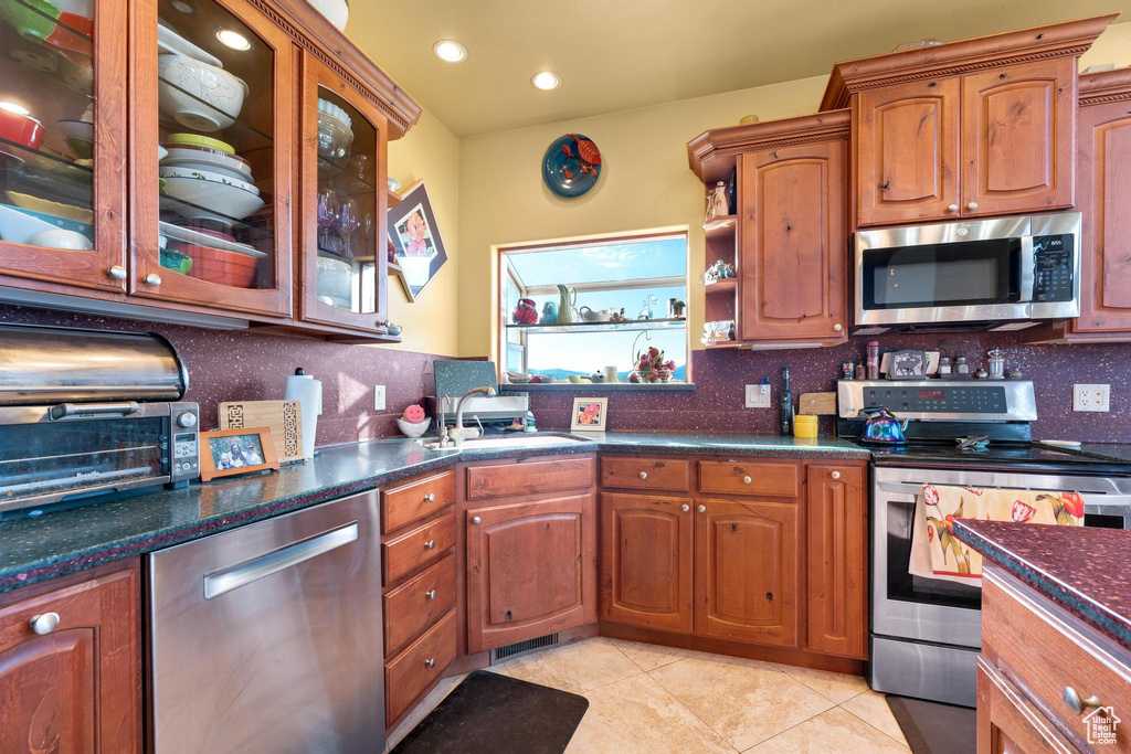 Kitchen featuring stainless steel appliances, light tile flooring, tasteful backsplash, and sink