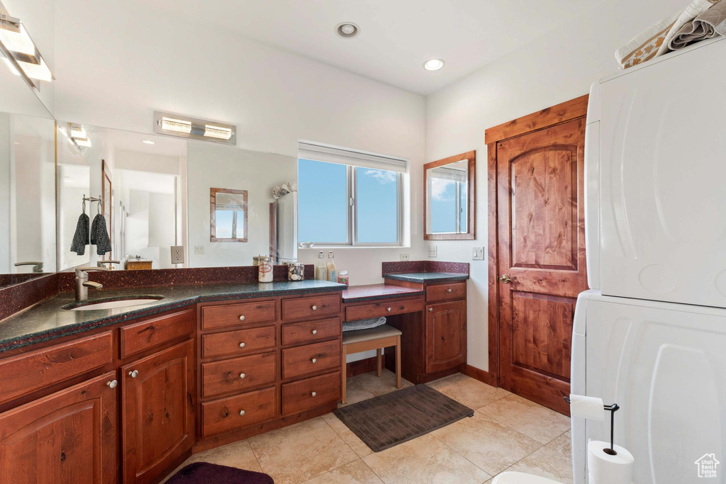 Bathroom with tile patterned flooring, vanity, and stacked washer / drying machine