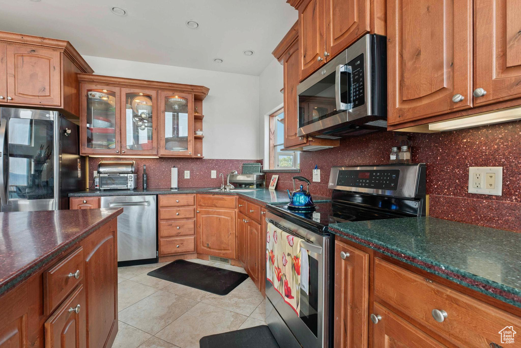 Kitchen with stainless steel appliances, light tile patterned floors, and decorative backsplash