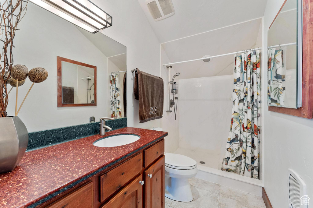 Bathroom featuring tile patterned floors, vaulted ceiling, toilet, a shower with curtain, and vanity