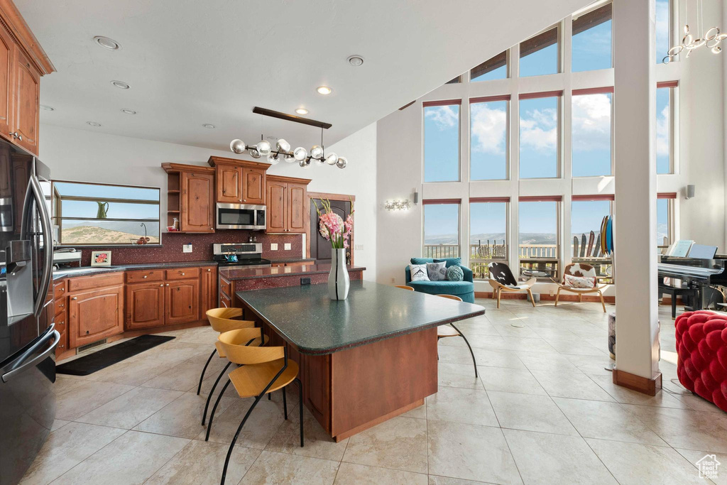 Kitchen featuring backsplash, a center island, stainless steel appliances, a high ceiling, and a breakfast bar area