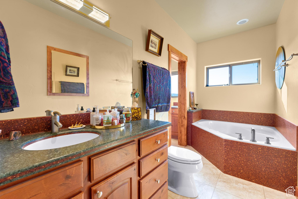 Bathroom with tiled tub, vanity, toilet, and tile floors