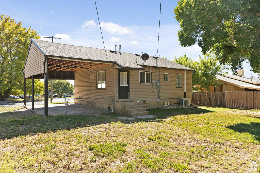 Back of property with a lawn and central AC unit