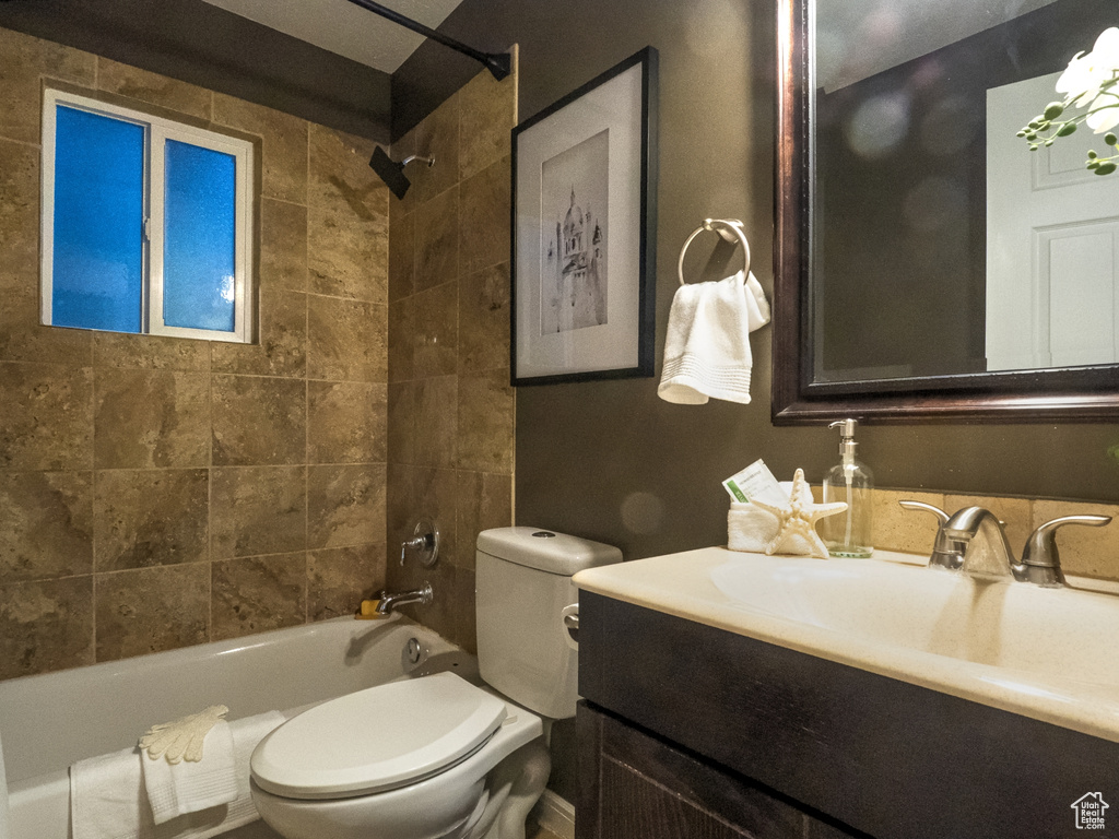 Full bathroom with tiled shower / bath, vanity, and toilet