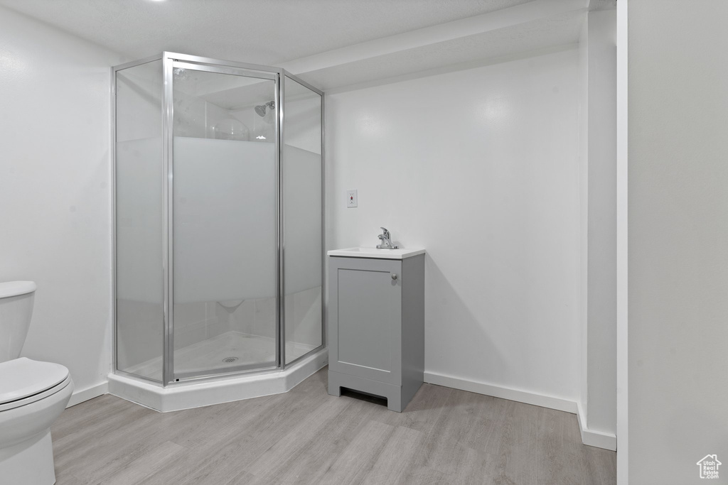 Bathroom featuring an enclosed shower, hardwood / wood-style flooring, vanity, and toilet