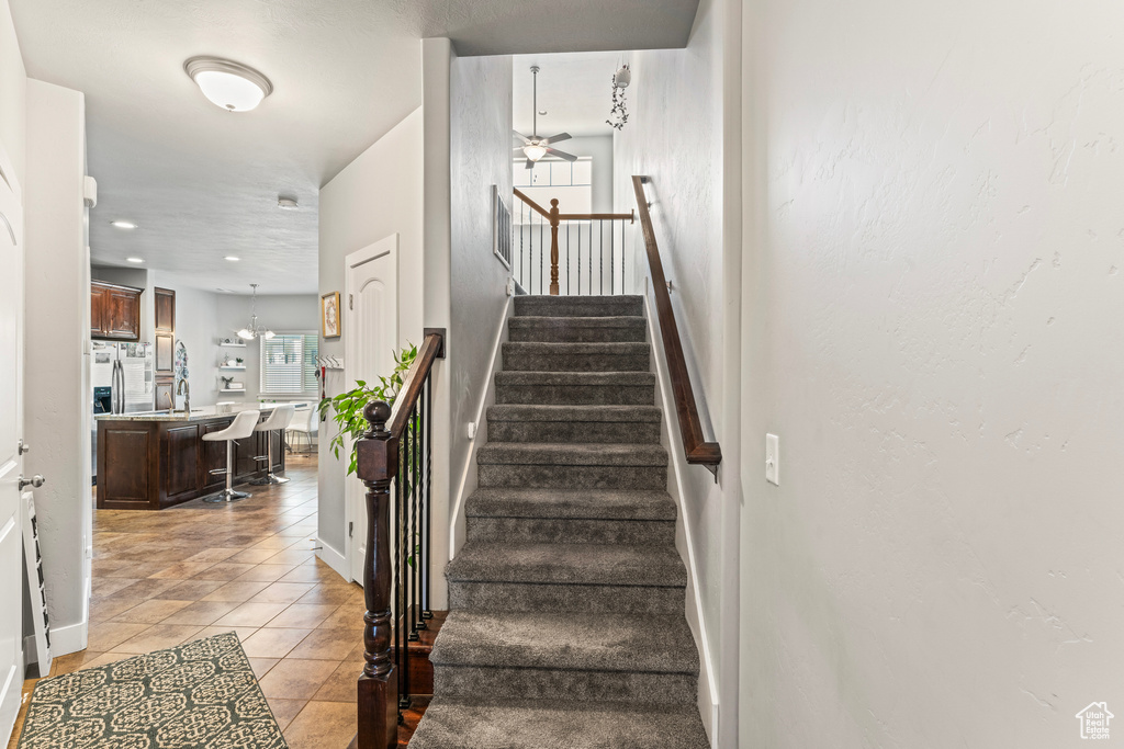 Stairway featuring ceiling fan and light tile floors