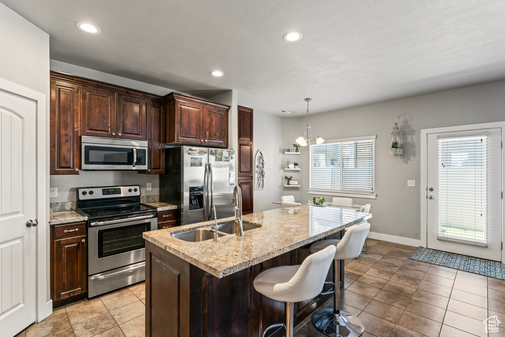Kitchen with appliances with stainless steel finishes, a kitchen island with sink, light tile floors, and a wealth of natural light