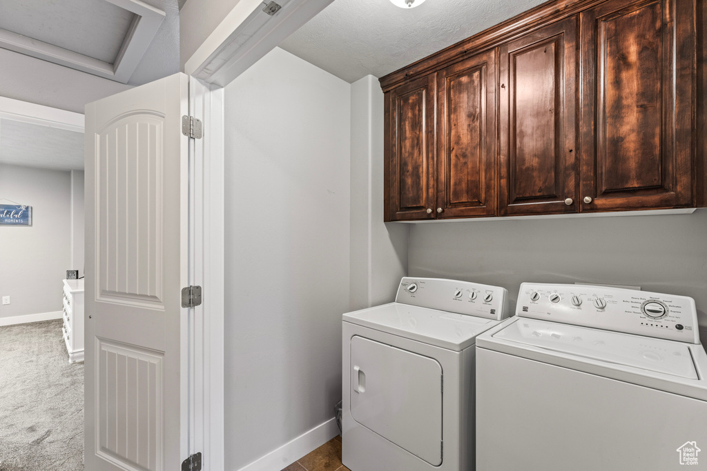 Washroom featuring washer and dryer, light colored carpet, and cabinets