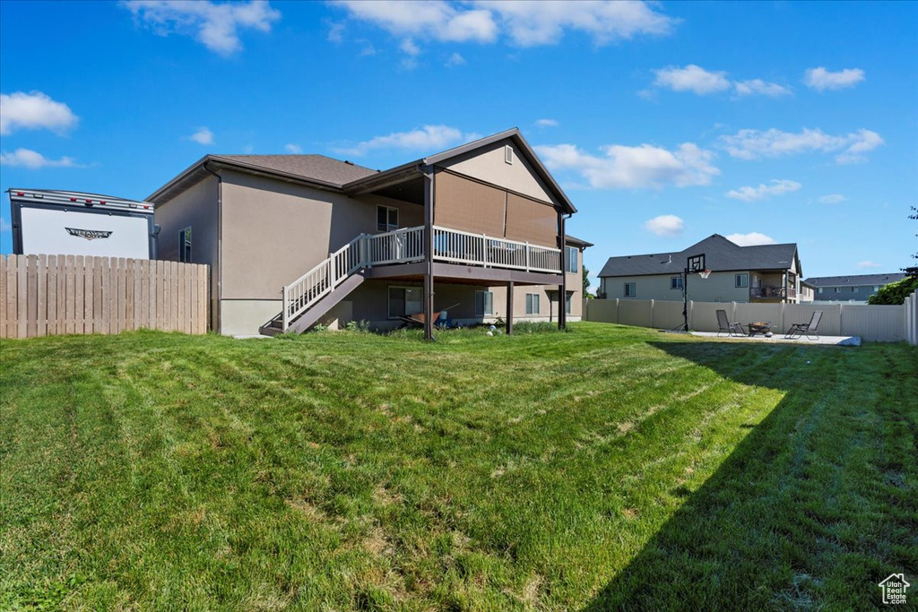 Rear view of house with a wooden deck and a yard