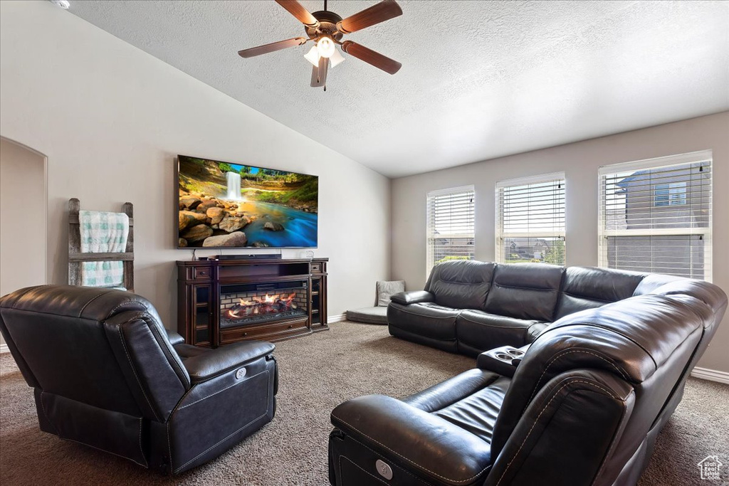 Carpeted living room with vaulted ceiling, ceiling fan, and a textured ceiling