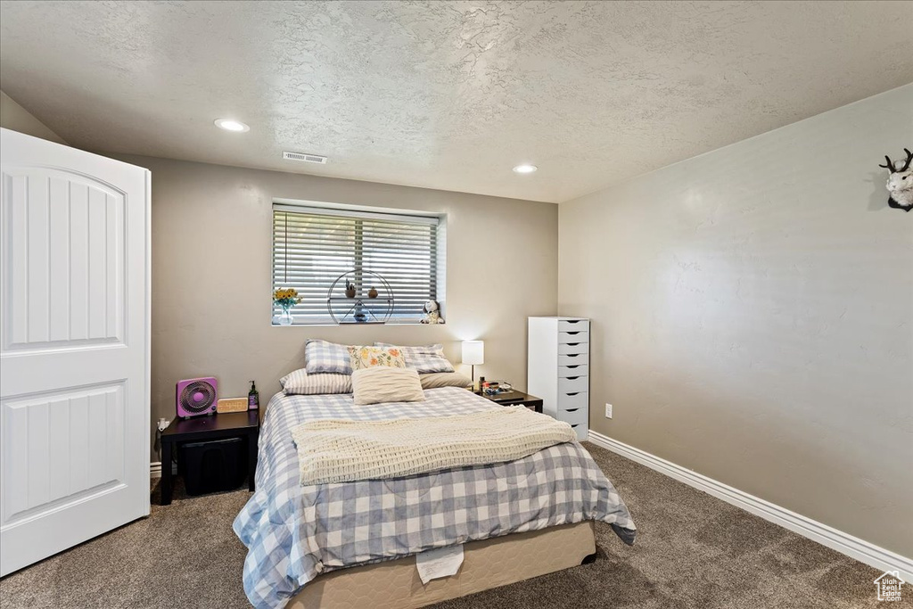 Bedroom with a textured ceiling and dark carpet