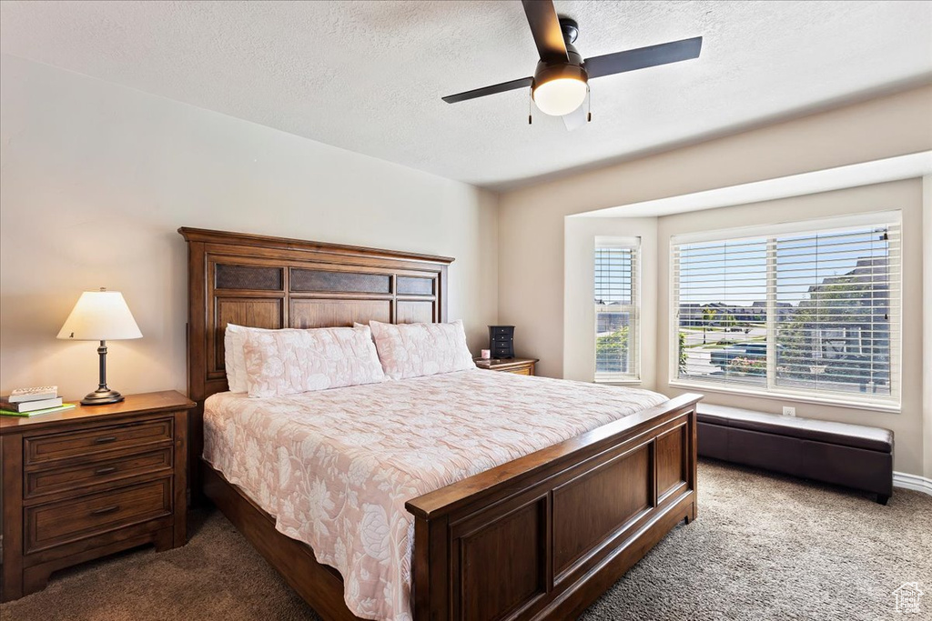 Bedroom featuring a textured ceiling, ceiling fan, and carpet floors