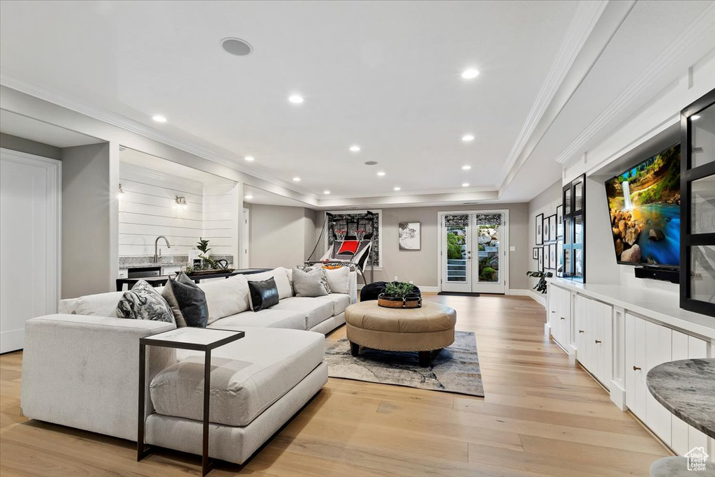 Living room with crown molding, french doors, and light wood-type flooring