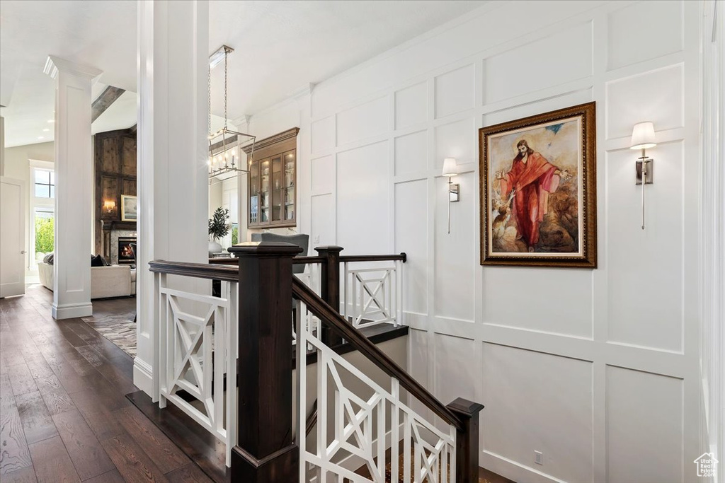 Hall with a chandelier, dark hardwood / wood-style floors, and ornate columns