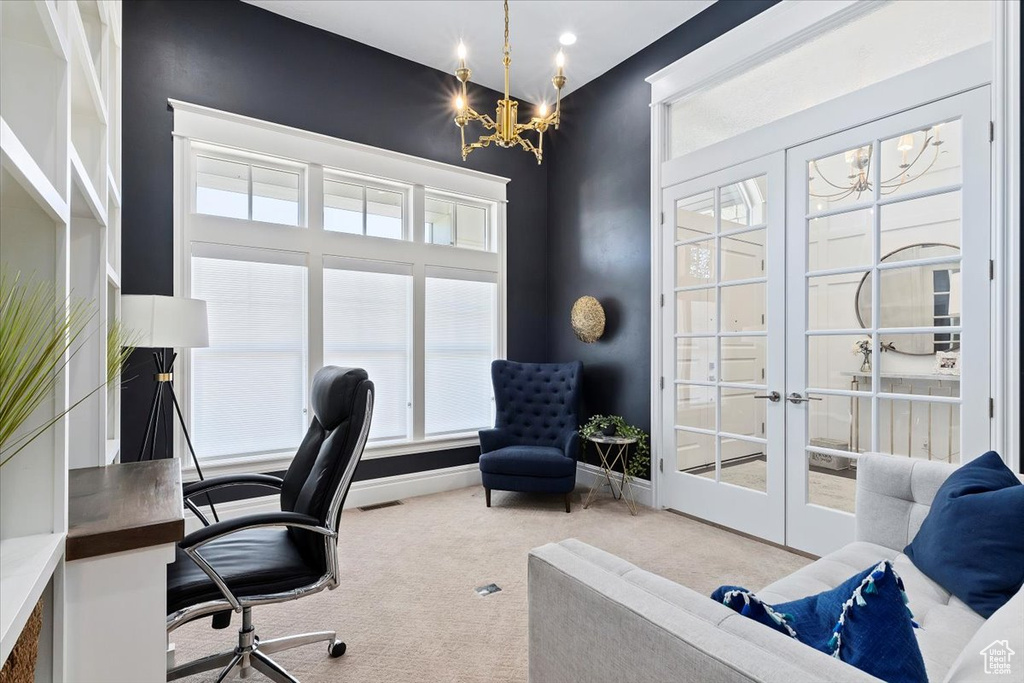 Home office with french doors, light colored carpet, and an inviting chandelier