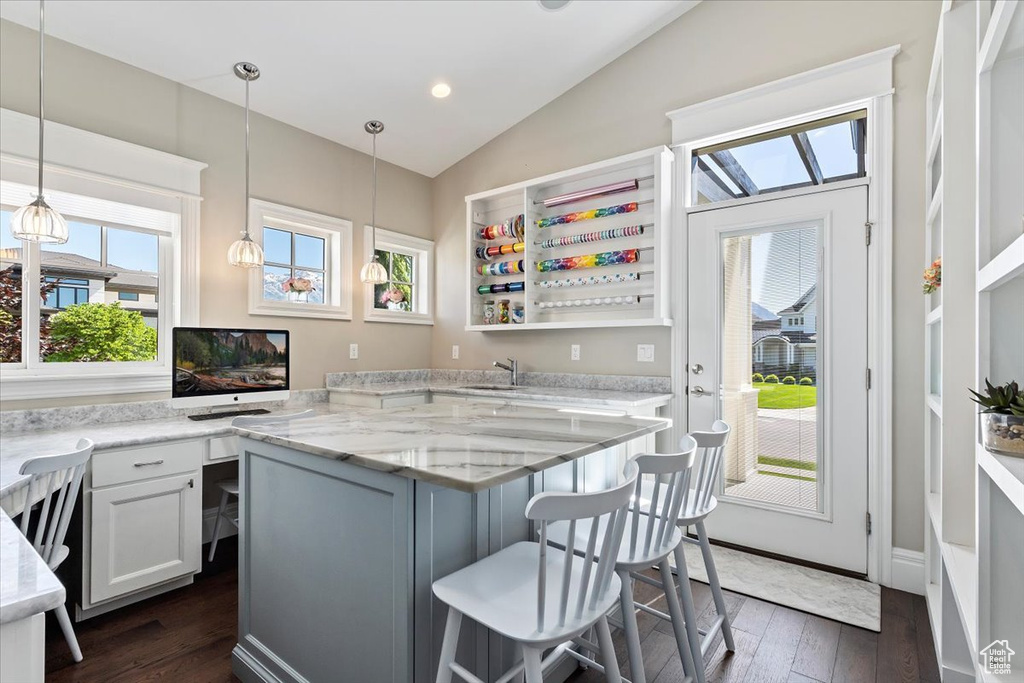 Kitchen with dark hardwood / wood-style floors, a breakfast bar area, a healthy amount of sunlight, and lofted ceiling