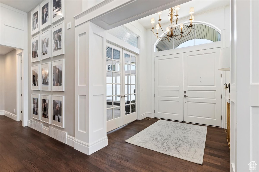 Entrance foyer with dark hardwood / wood-style floors, french doors, and a chandelier