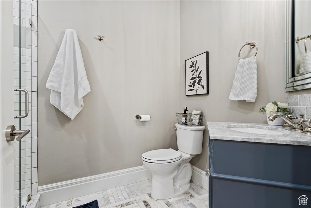 Bathroom featuring a shower with door, vanity, and toilet