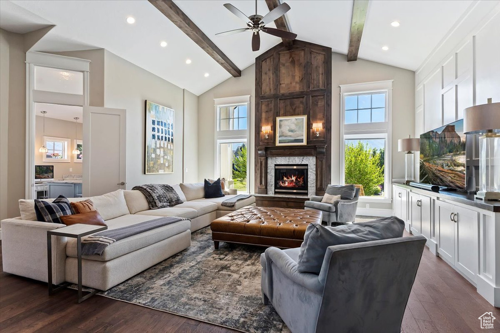 Living room featuring a fireplace, dark hardwood / wood-style floors, beam ceiling, high vaulted ceiling, and ceiling fan