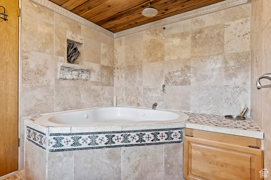 Bathroom featuring a relaxing tiled bath, wood ceiling, and tile walls