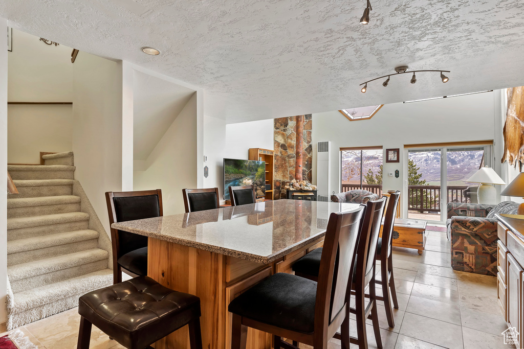 Tiled dining area featuring a textured ceiling and rail lighting