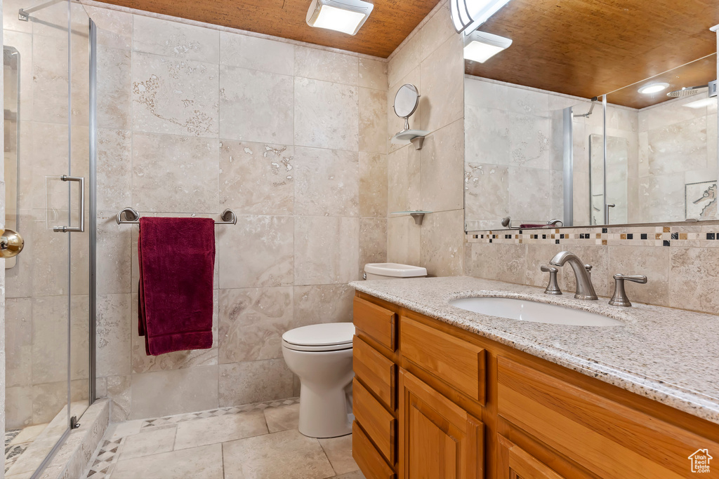 Bathroom featuring tile flooring, wooden ceiling, tile walls, large vanity, and toilet