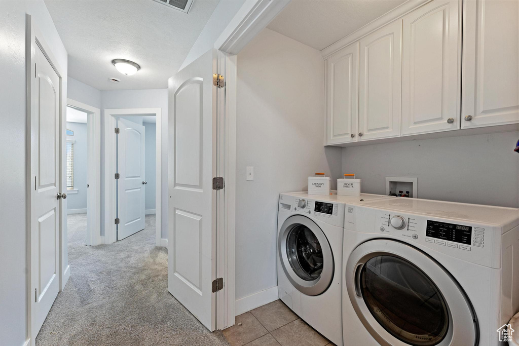 Washroom with light carpet, cabinets, washing machine and dryer, and washer hookup