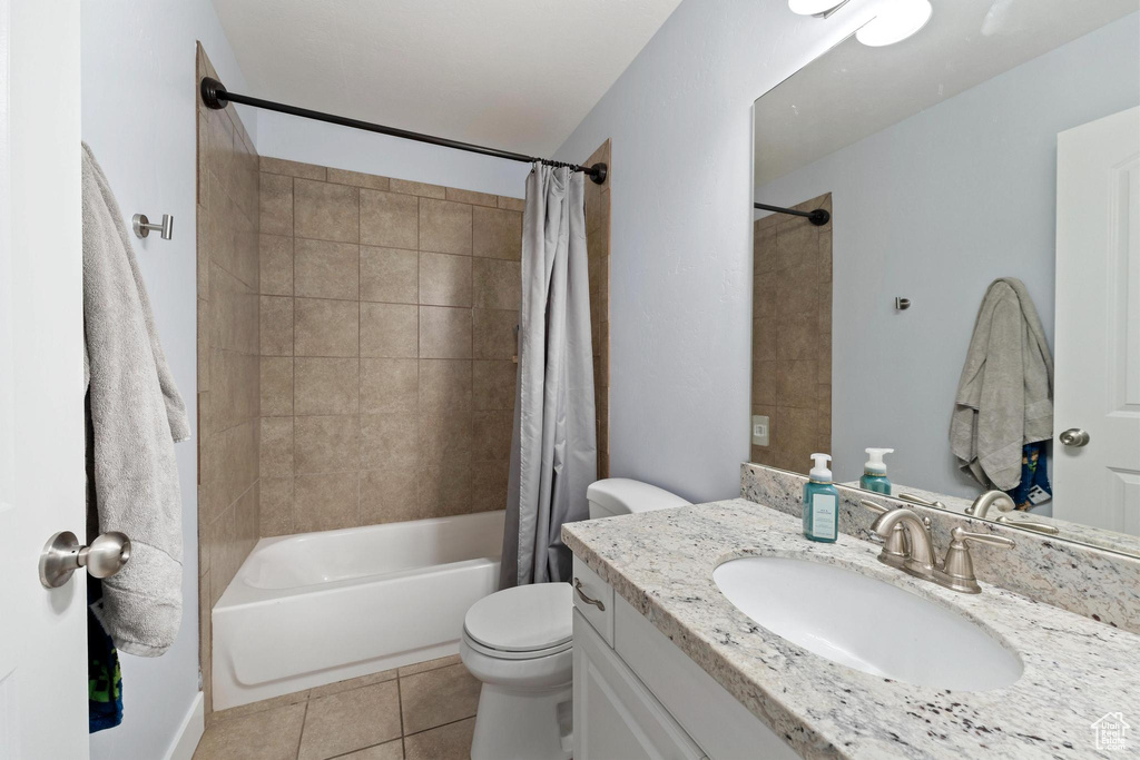 Full bathroom with tile flooring, toilet, shower / bathtub combination with curtain, and large vanity