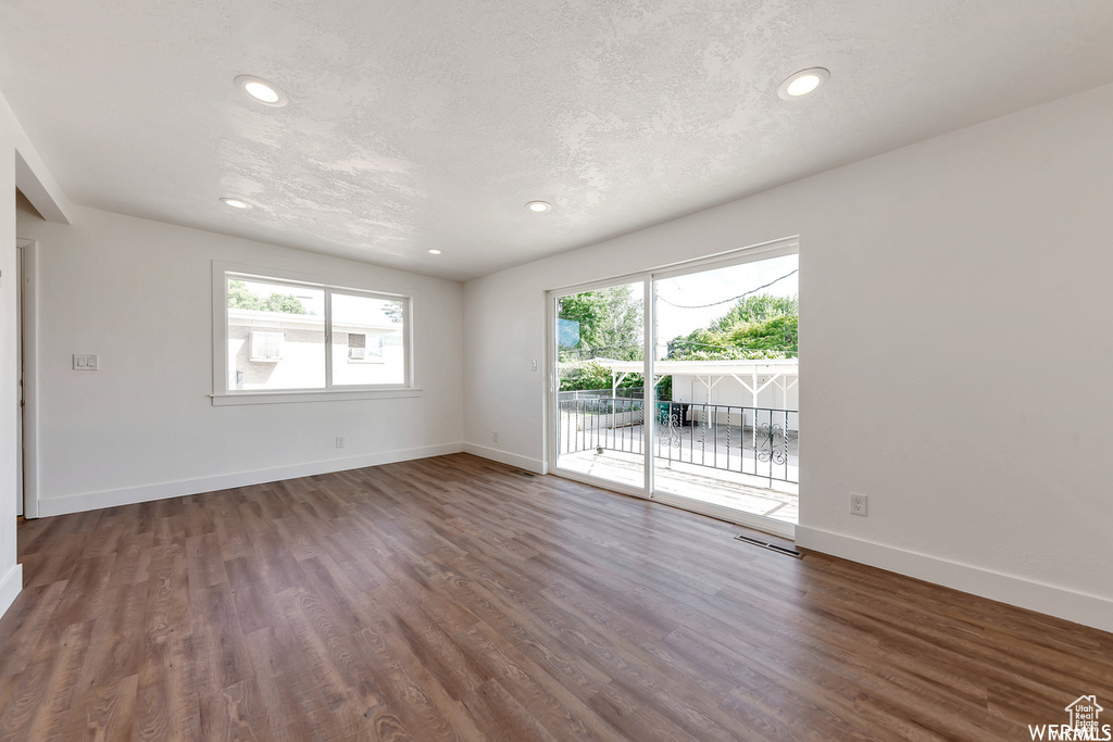 Empty room with a textured ceiling and dark wood-type flooring