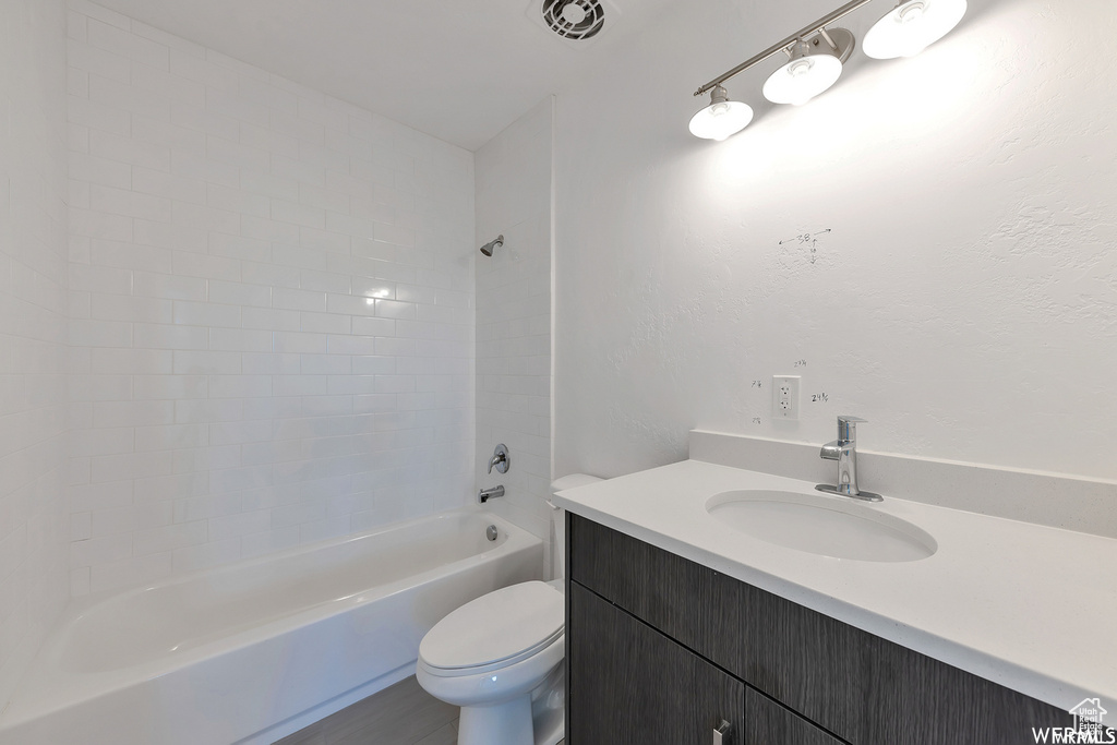 Full bathroom with tiled shower / bath combo, vanity, and toilet