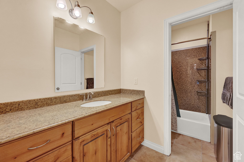 Bathroom featuring tiled shower / bath, vanity, and tile flooring