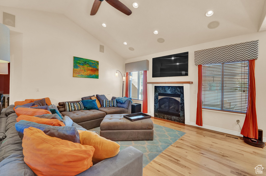 Living room with ceiling fan, a fireplace, lofted ceiling, and wood-type flooring