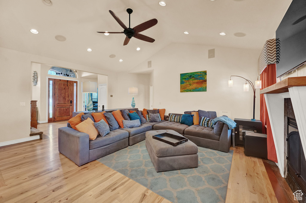 Living room featuring high vaulted ceiling, ceiling fan, and light hardwood / wood-style floors