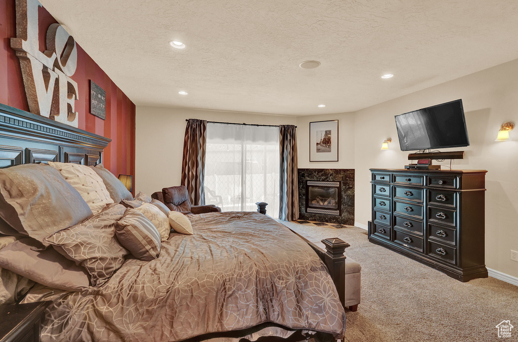 Bedroom featuring a premium fireplace, a textured ceiling, and carpet