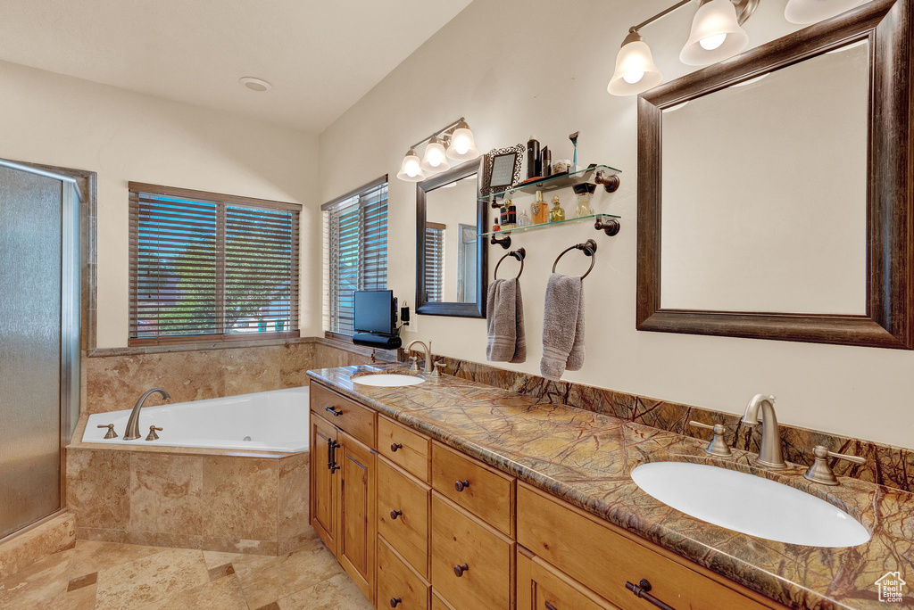 Bathroom with a relaxing tiled bath, tile flooring, and double sink vanity