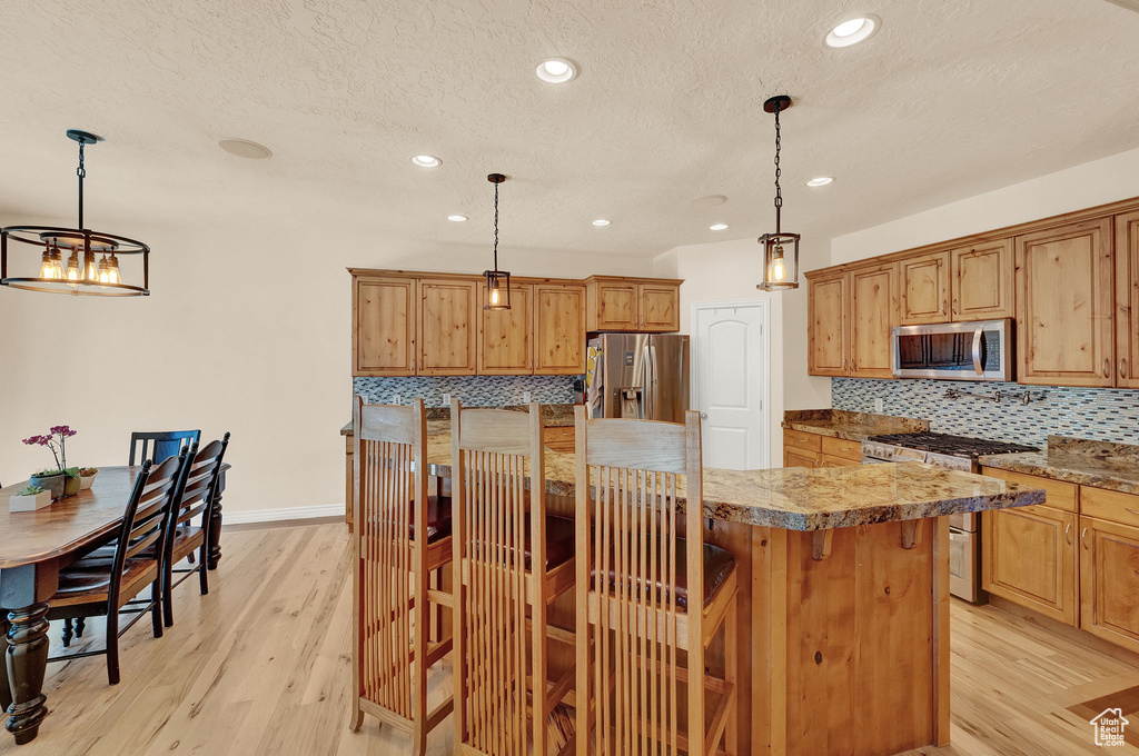 Kitchen with backsplash, pendant lighting, a kitchen bar, and stainless steel appliances