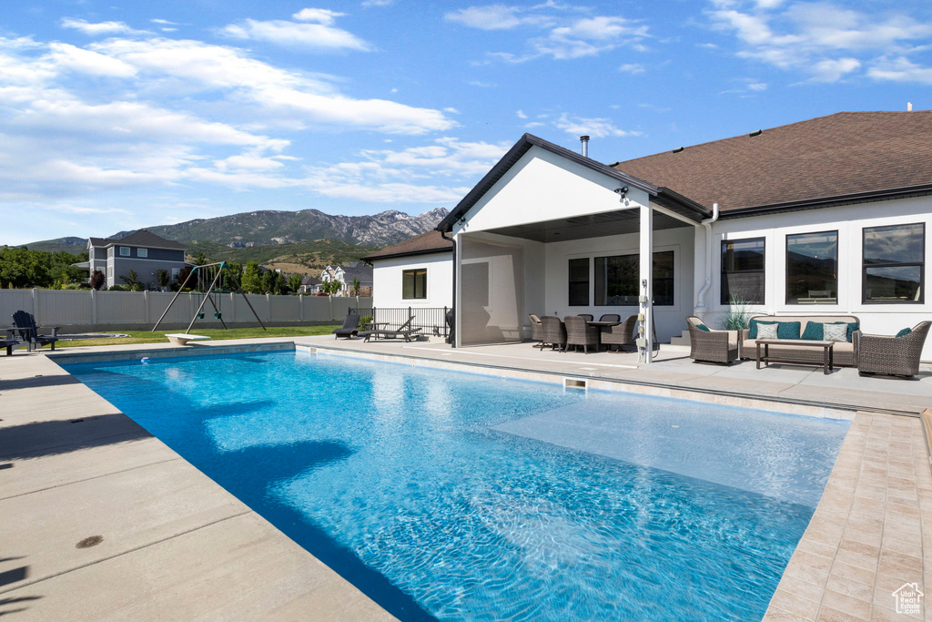 View of swimming pool featuring an outdoor living space, a patio area, a mountain view, and a diving board