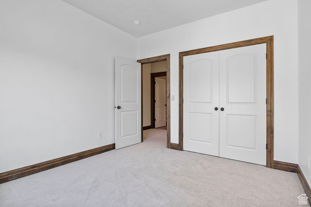 Unfurnished bedroom with light colored carpet and a closet