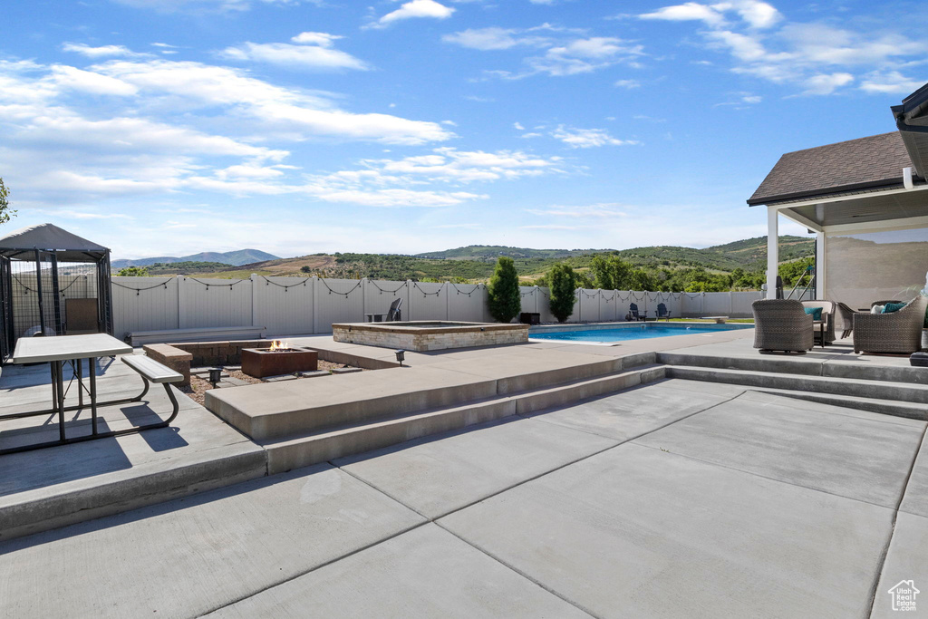 View of patio with a mountain view, a fire pit, and a fenced in pool