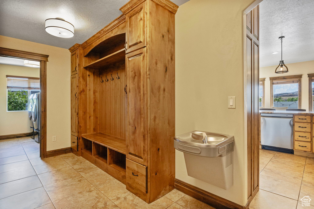 Mudroom with a textured ceiling, a wealth of natural light, and light tile floors