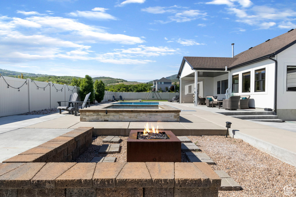 View of terrace featuring a fire pit and a swimming pool with hot tub